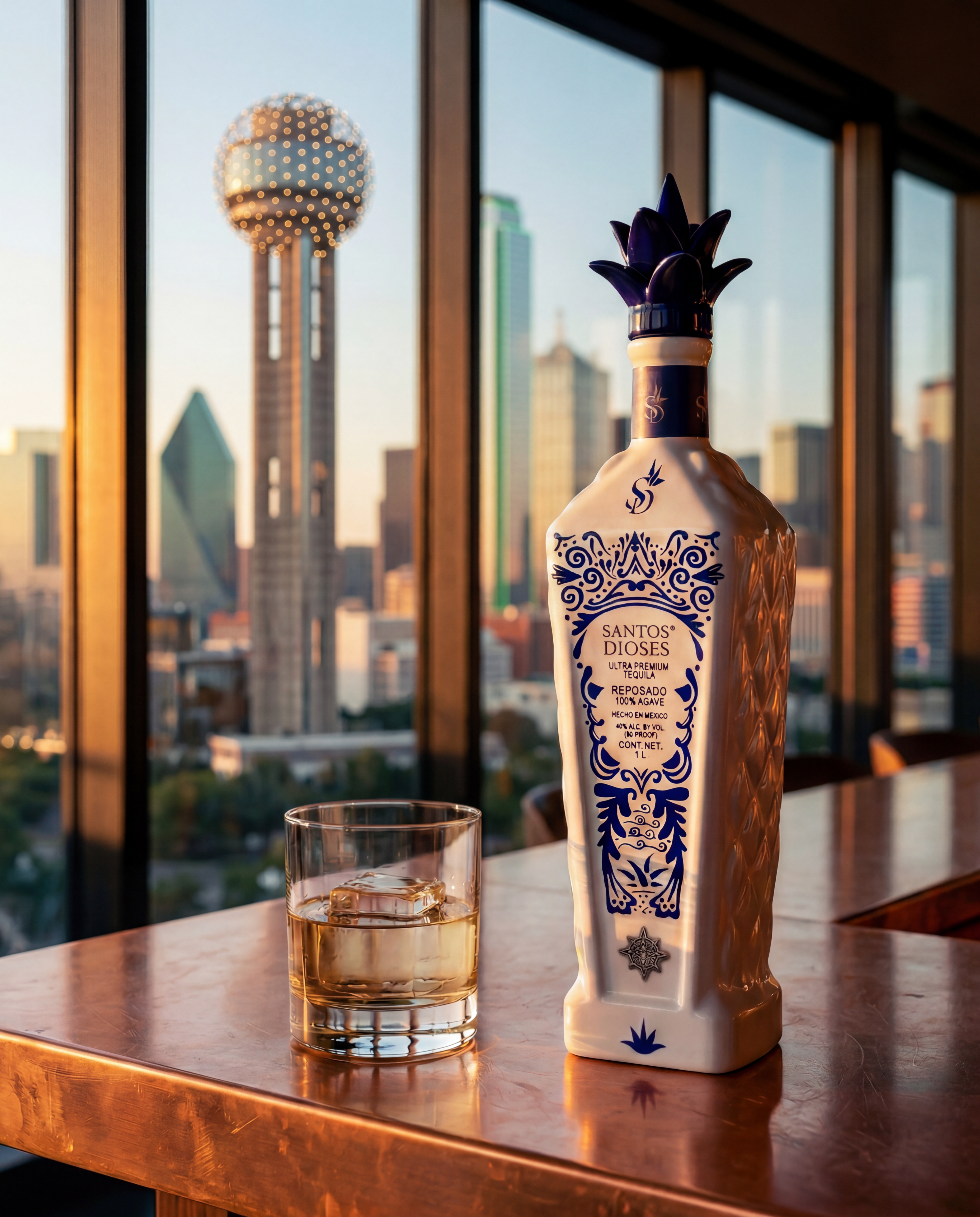 Santos Dioses Reposado bottle on a copper bar inside a Dallas rooftop interior at golden hour, Dallas skyline with Reunion Tower visible through the windows